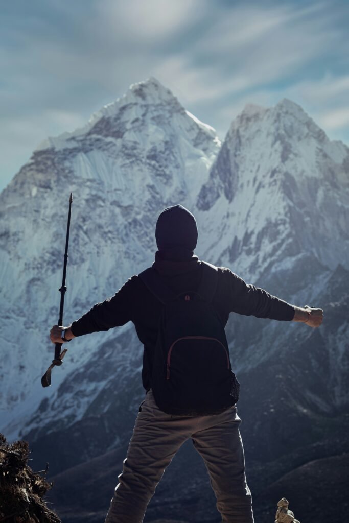 a man holding a rifle while standing on top of a mountain